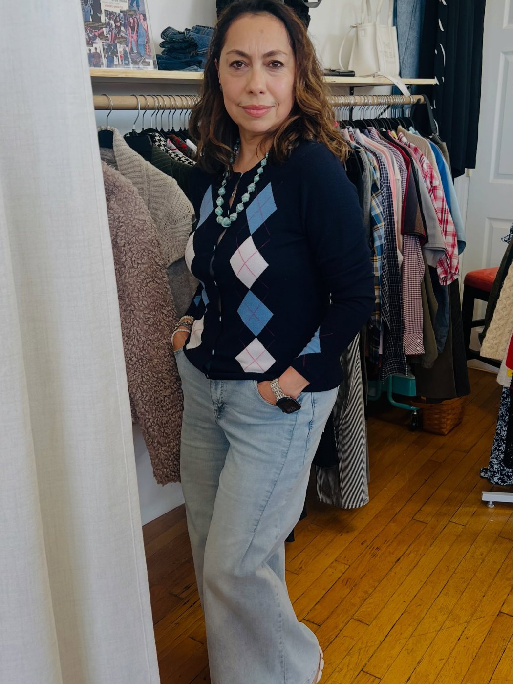A customer wearing an argyle cardigan with a turquoise necklace in the shop